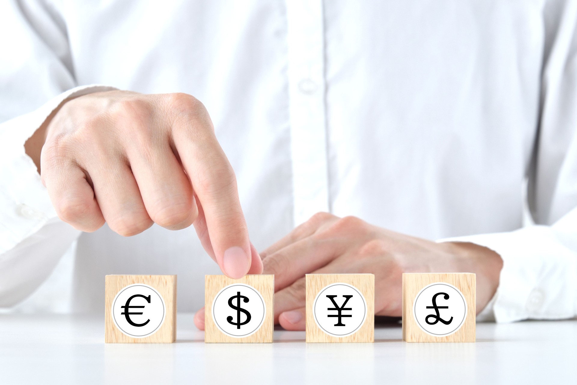 Human choosing which wooden block with various currency symbol is best